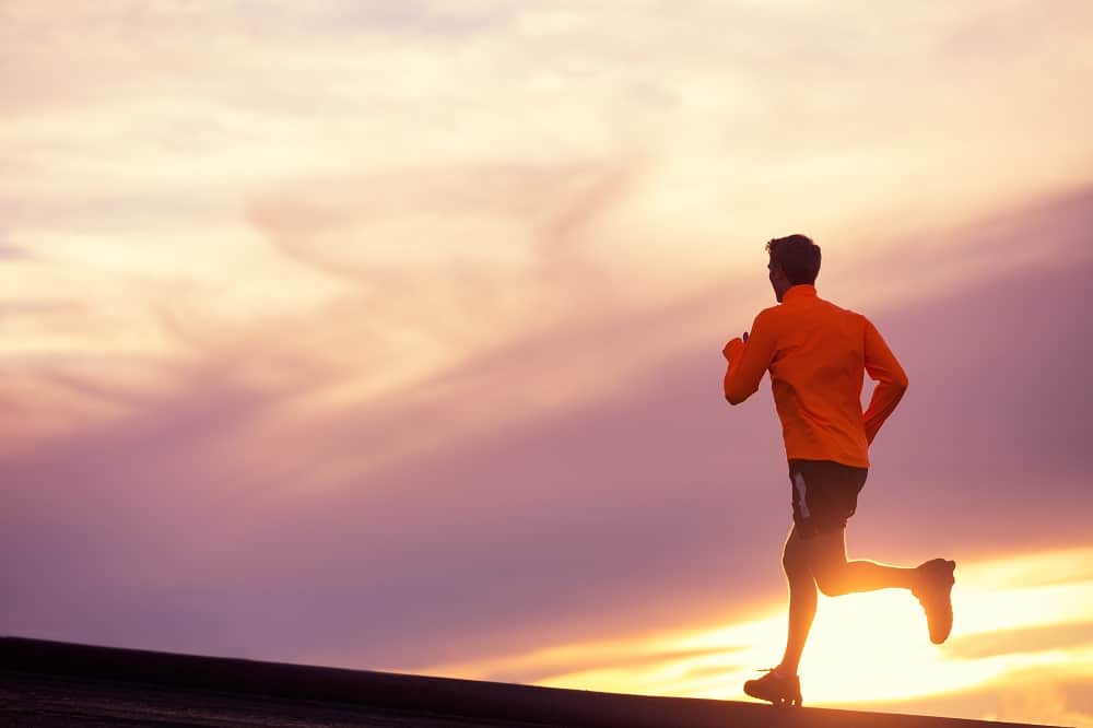 a man doing a long distance run at sunset outside