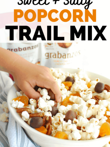 a kids hand reaching into a bowl of popcorn trail mix to grab some