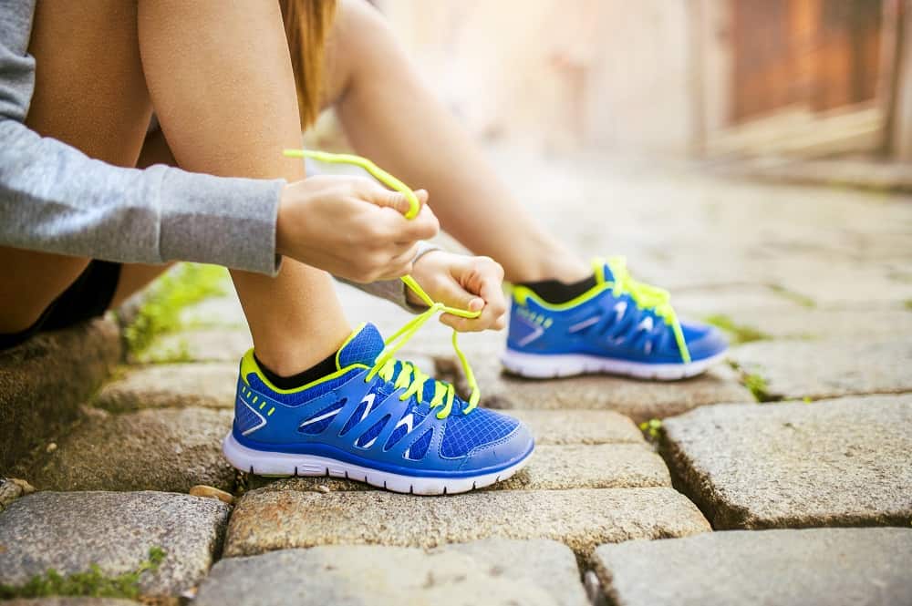 a woman lacing up her sneakers getting ready to go for a run