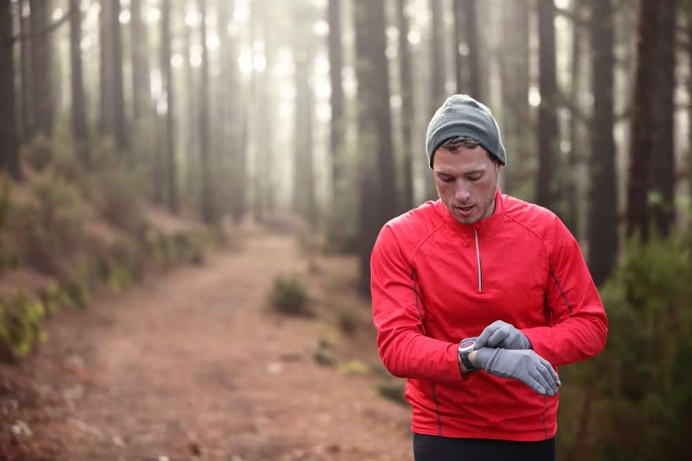 trail runner looking at his heart rate monitor watch