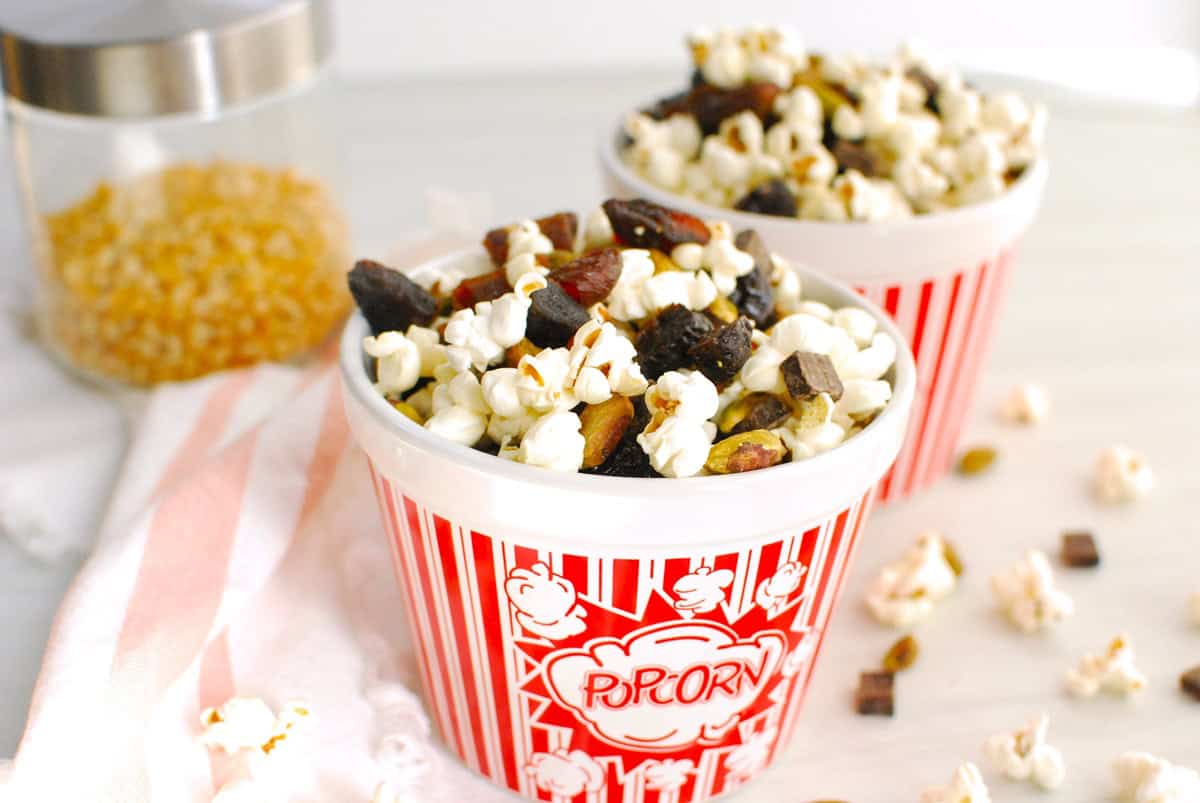 Two red and white popcorn bowls filled with popcorn trail mix.