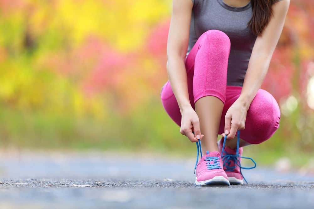 a woman tying her shoes outside in preparation to go for a run