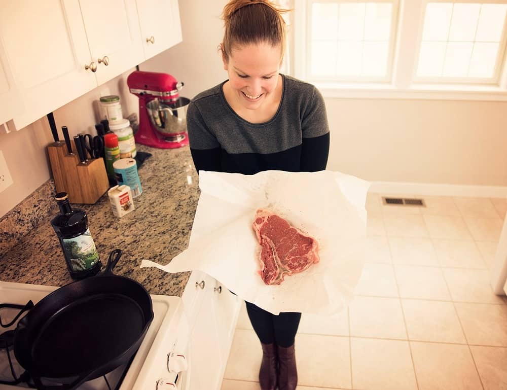 a woman holding a steak in butcher paper