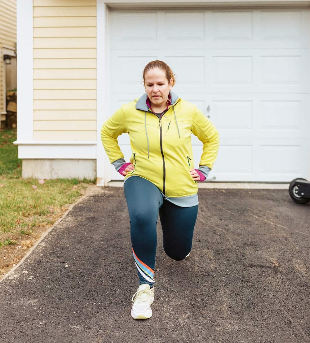 a woman doing forward lunges outside during a bodyweight workout