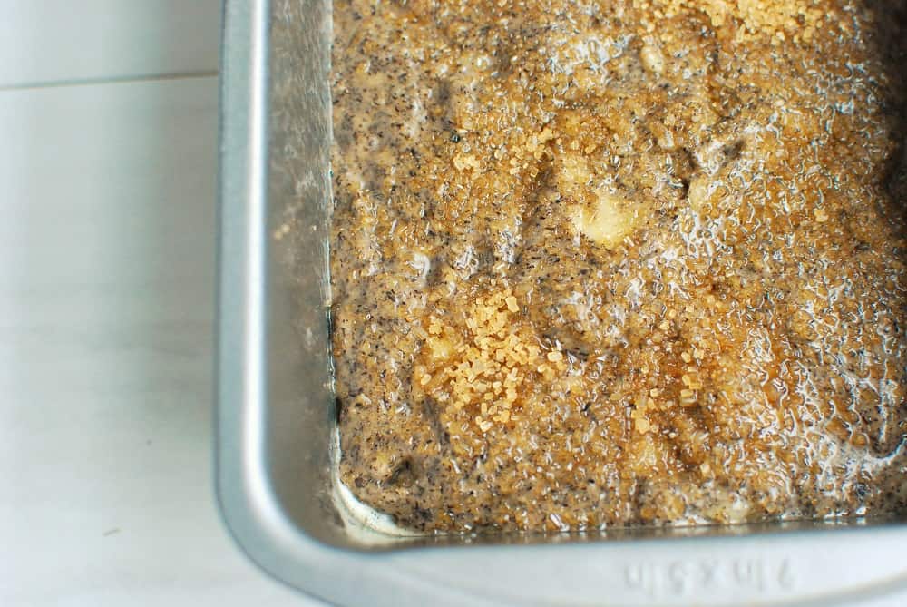 a close up of turbinado sugar on top of banana bread batter in a loaf pan