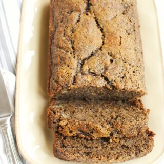 a loaf of buckwheat banana bread on a plate with two slices cut