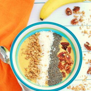 a pumpkin smoothie bowl with toppings of granola, chia seeds, coconut, and pecans