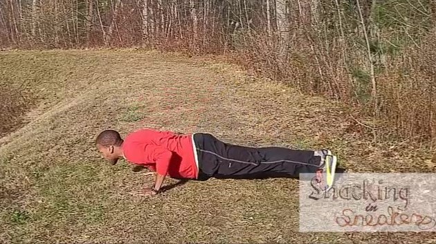 a man doing standard pushups outside on the grass