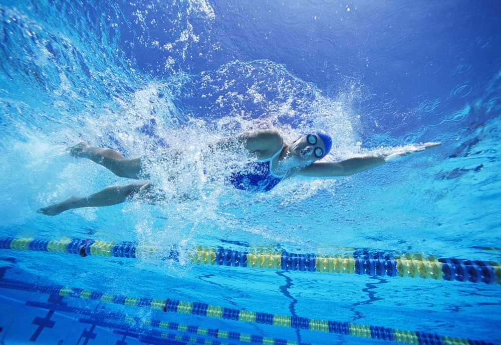 a woman working on swimming drills in a large pool