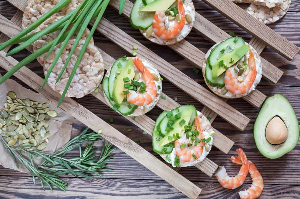 Rice cakes with sliced avocado cucumber shrimp and cream cheese. Fresh parsley and rosemary. 