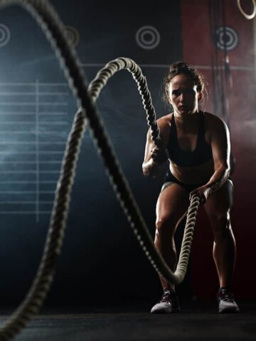 A woman exercising with ropes in the gym.