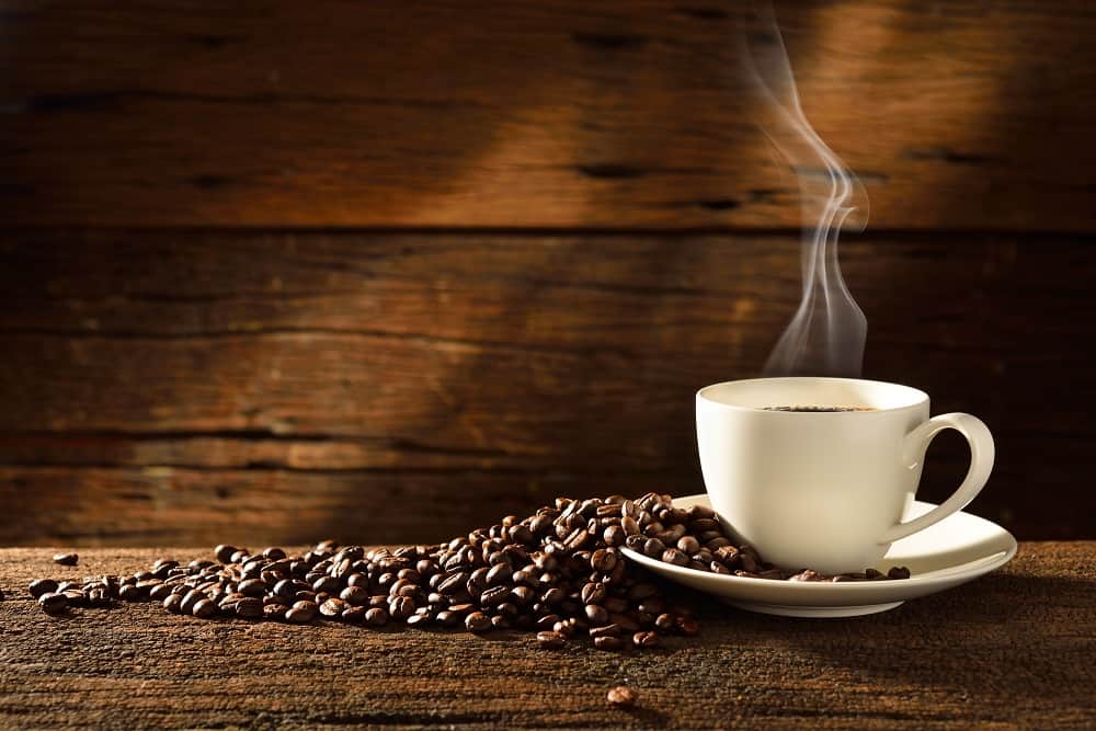 a cup of coffee next to some coffee beans