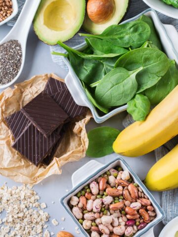 A variety of foods for runners that are rich in magnesium like nuts, spinach, dark chocolate, and seeds.