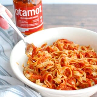 a bowl of sourdough pasta with red sauce, and a fork picking up a bite of pasta