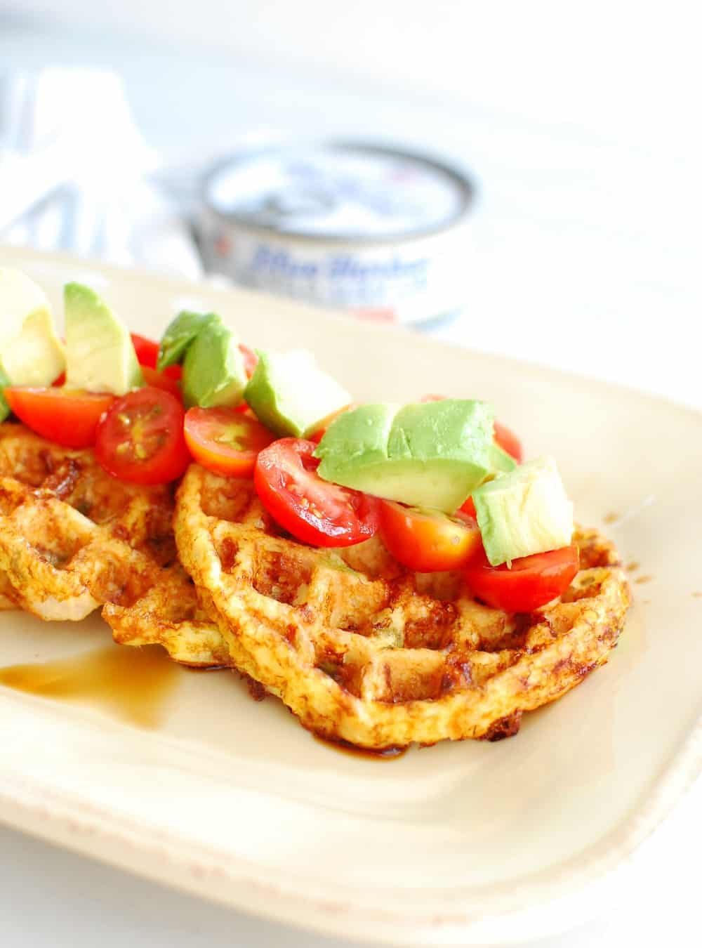 a tuna waffle topped with tomatoes, avocado, and balsamic