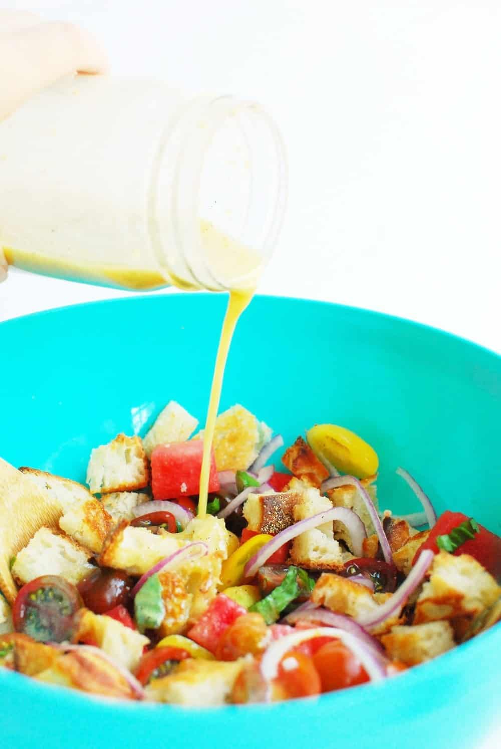 a woman pouring dressing onto a bowl of salad