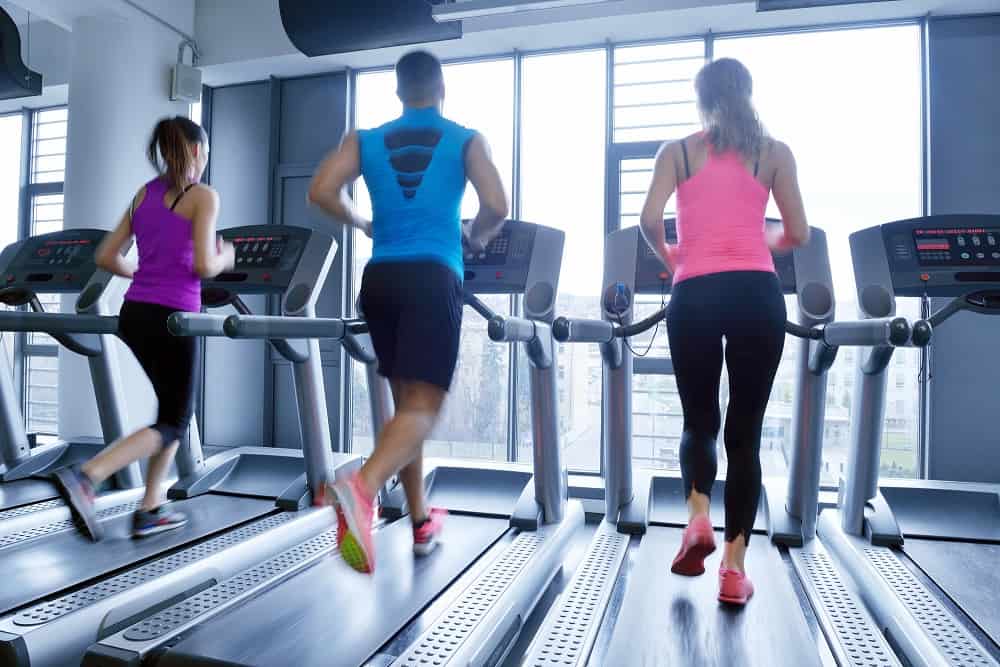 three treadmills with people running on them