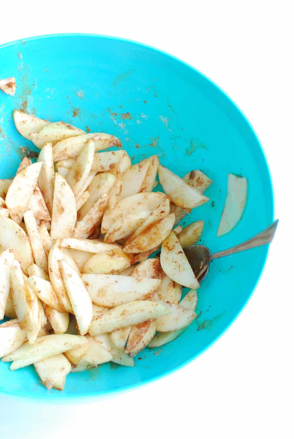 a bowl of sliced apples tossed with honey, flour, lemon juice, and cinnamon