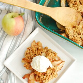 honey apple crisp on a plate topped with a scoop of ice cream, next to the baking dish with it too