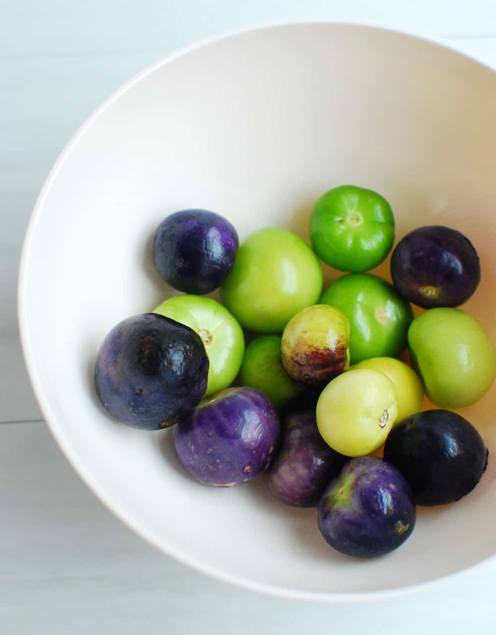 a bowl of green and purple tomatillos