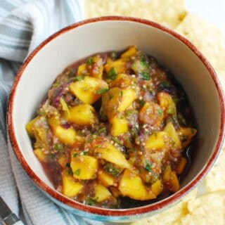 a bowl of mango tomatillo salsa next to some tortilla chips