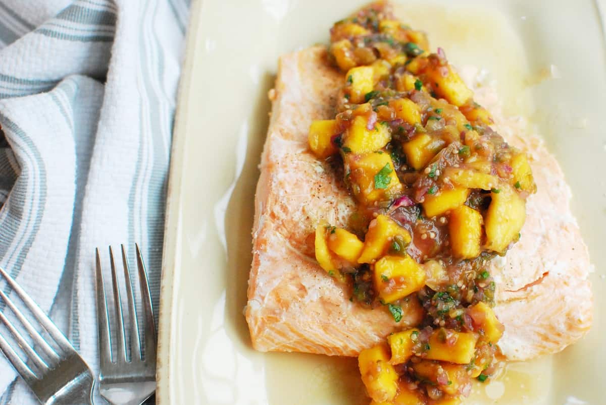 baked salmon topped with mango tomatillo salsa on a plate