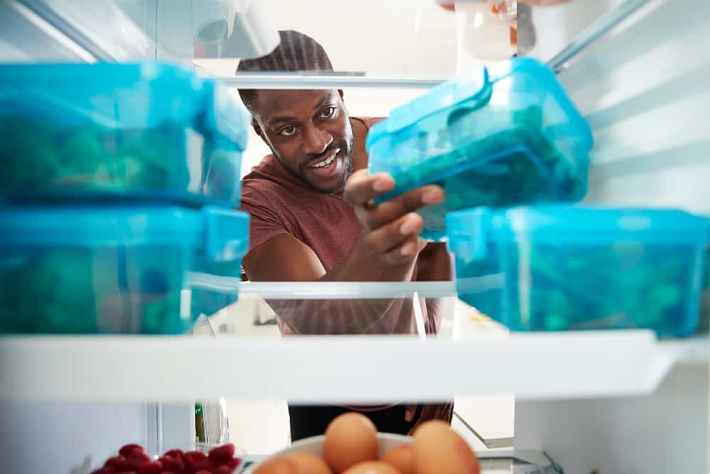 a man grabbing a meal prep container out of the fridge
