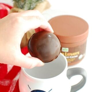 a woman placing a hot chocolate bomb into a mug