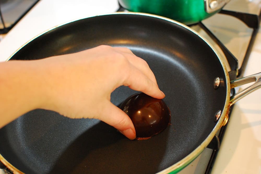 holding a chocolate half circle on a hot skillet