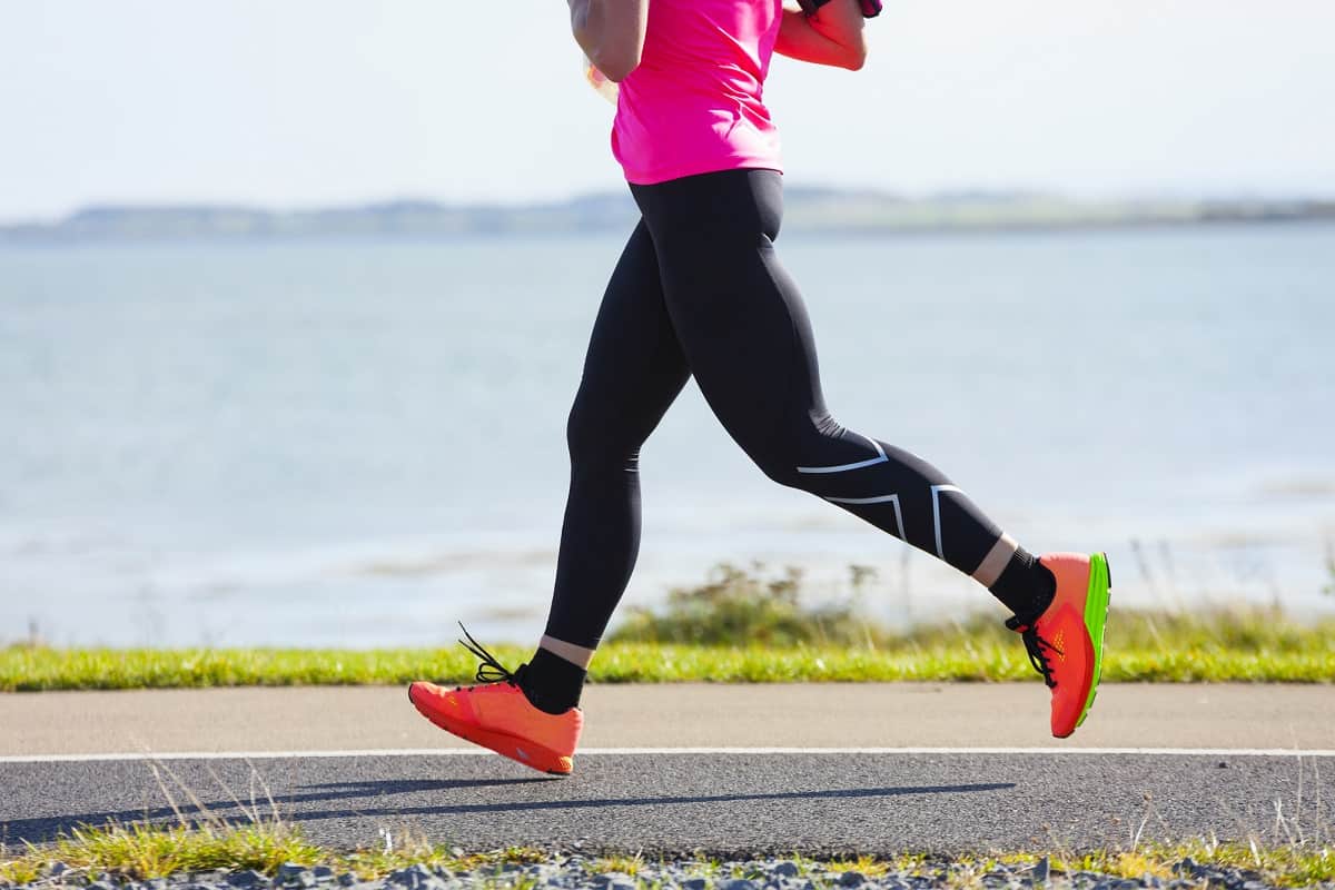 a female running outside on a path next to water