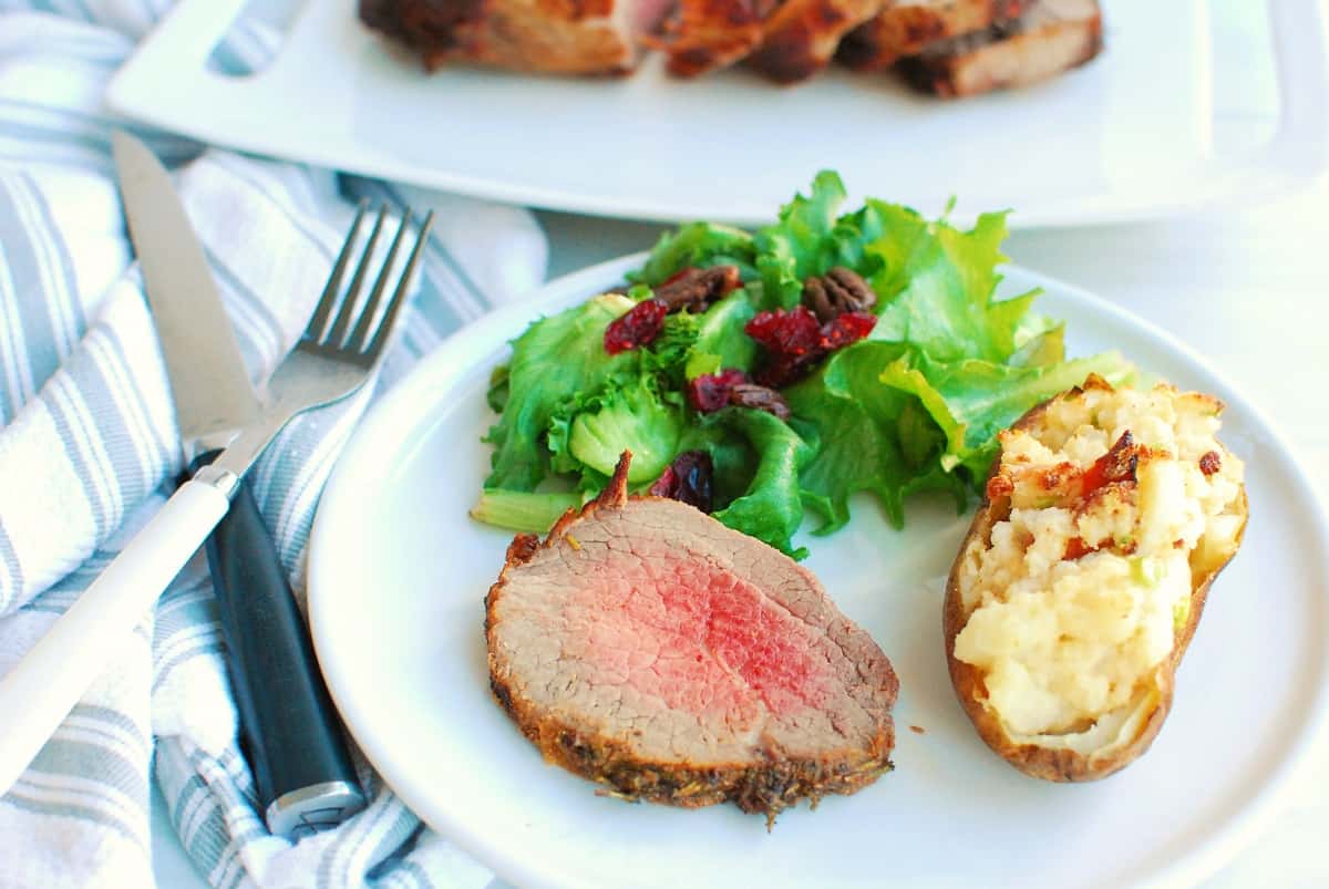 a piece of air fryer beef roast on a plate with salad and a potato