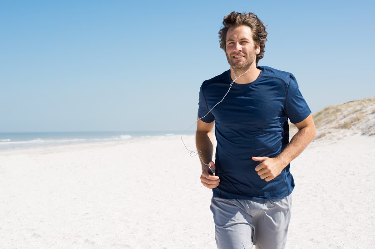 a male jogger who is running on the beach