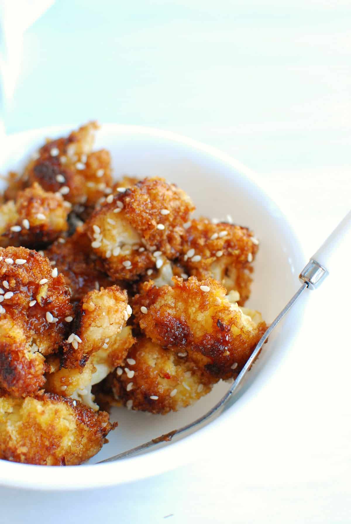 a bowl with teriyaki cauliflower and a fork leaning against the side of the bowl