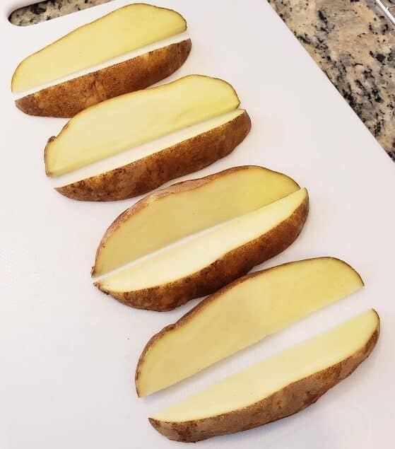 A potato cut into 8 wedges on a cutting board