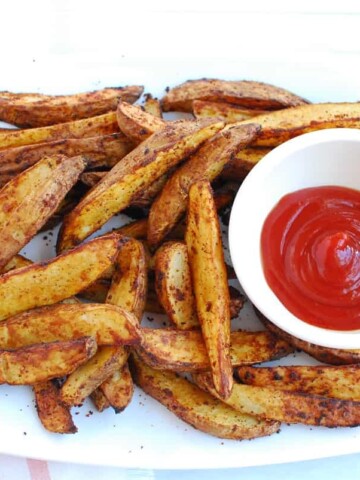 A platter of air fryer potato wedges with a small bowl of ketchup.