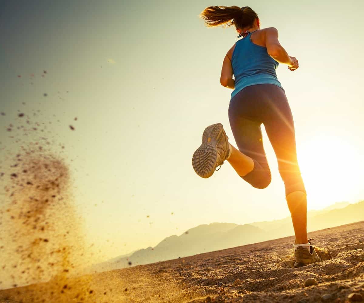 Young lady running in a desert at sunset