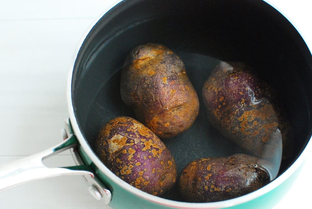 Purple potatoes in a pot of water.