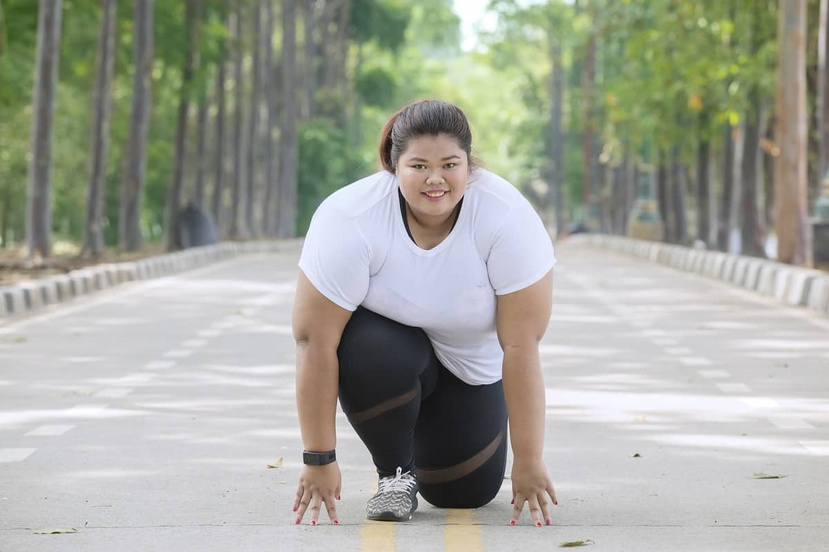 A woman kneeling on the ground getting ready to run.