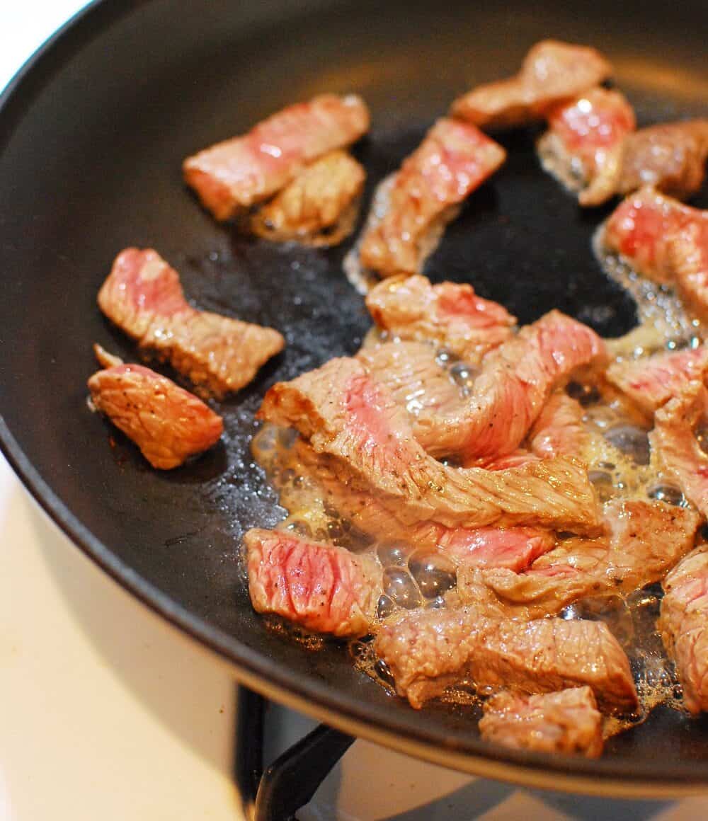 Steak cooking in a skillet.