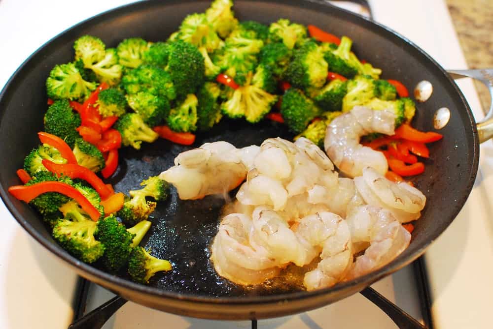 Veggies and shrimp in a skillet, cooking.