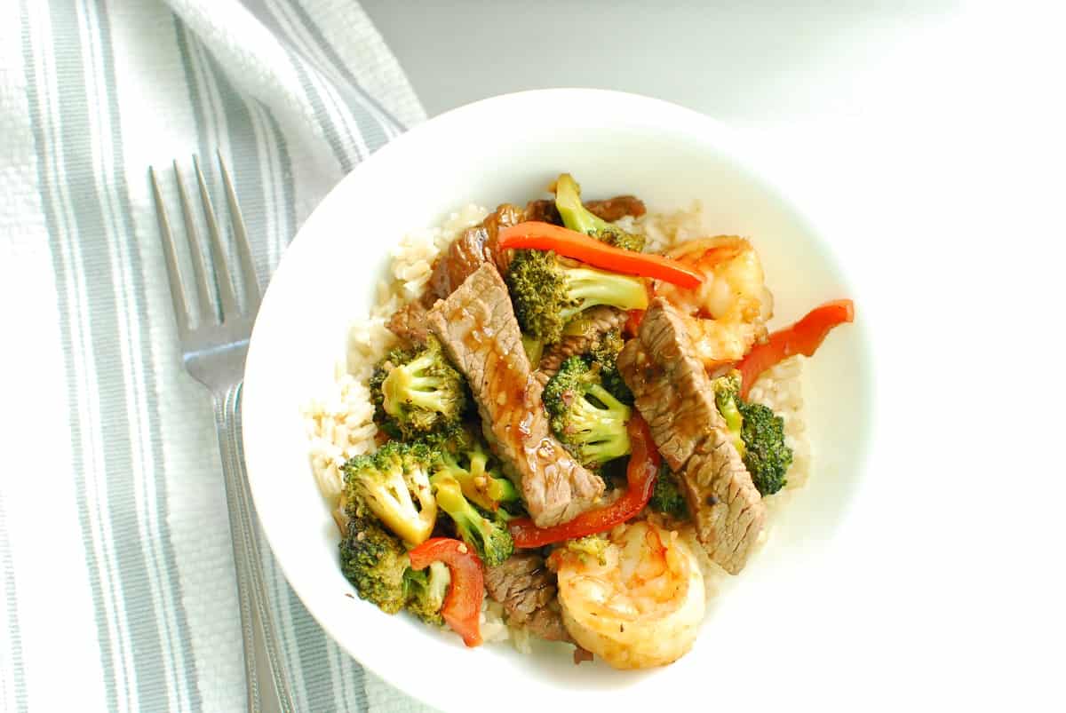 A bowl of steak and shrimp stir fry served over rice.