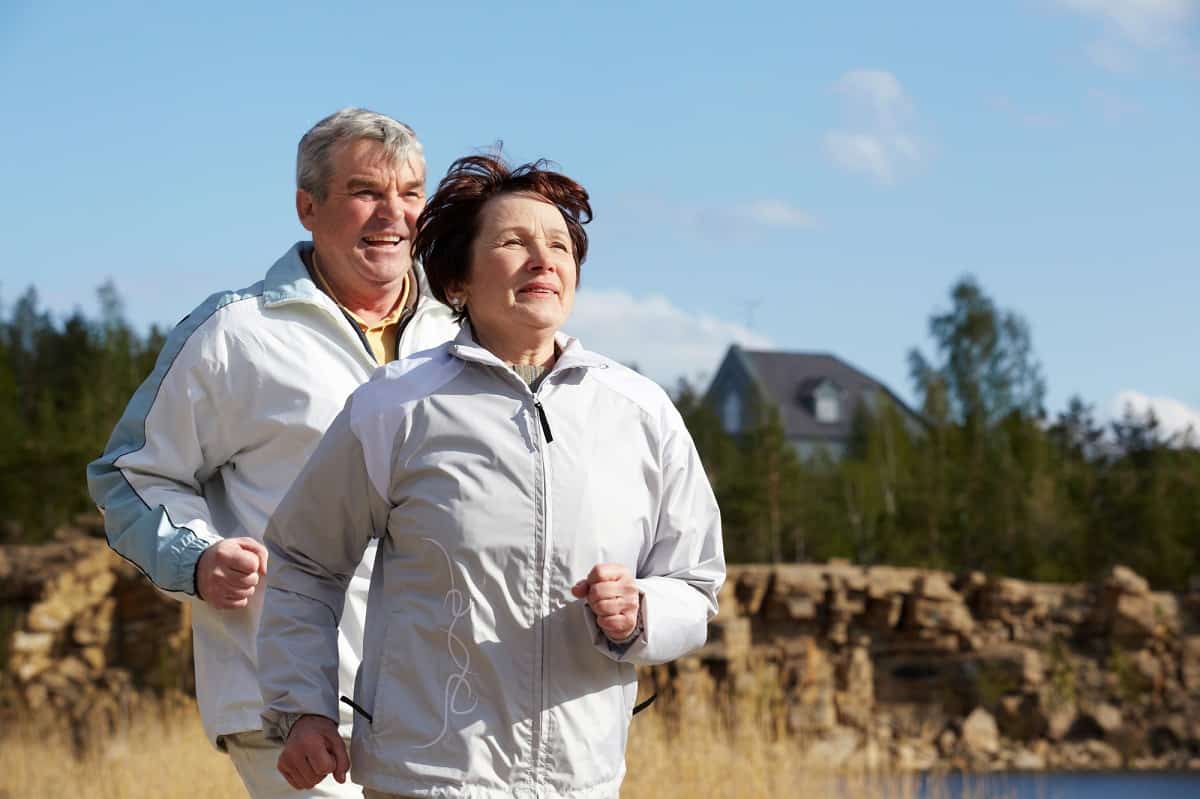 An older male and female running training together outside.