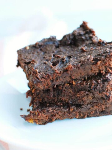 A stack of several butternut squash brownies on a plate next to a fork and napkin.