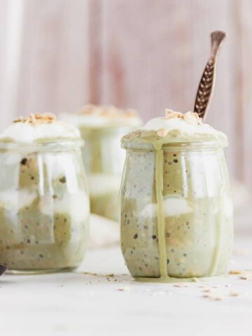 Several jars of matcha overnight oats, one of which has a spoon in it.