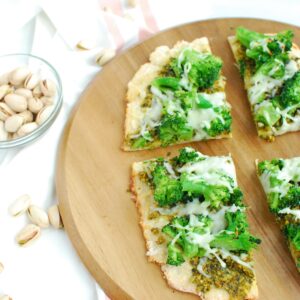 Several slices of pistachio pesto pizza on a cutting board.