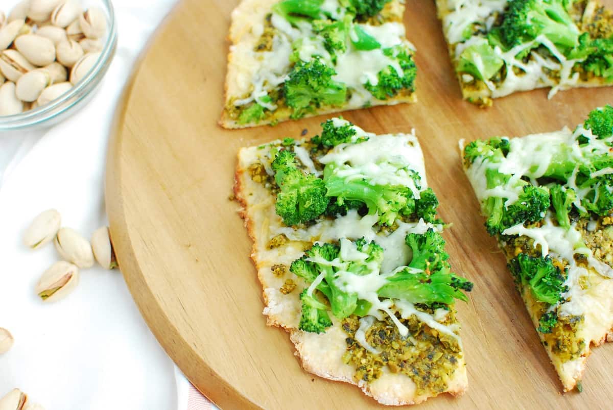 Close up of a slice of pistachio pesto pizza topped with broccoli and mozzarella.