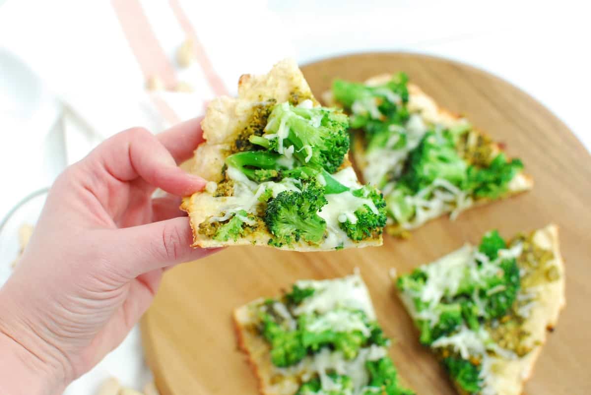 A woman's hand holding a piece of pizza.