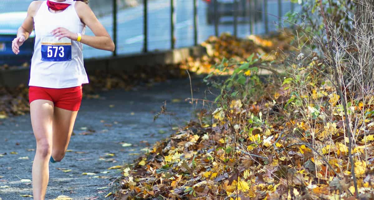 A sub 30 minute 50K runner coming around a turn on a paved path.