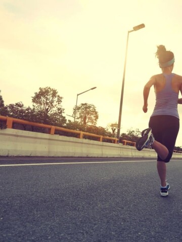A female runner who is running on the street outside.
