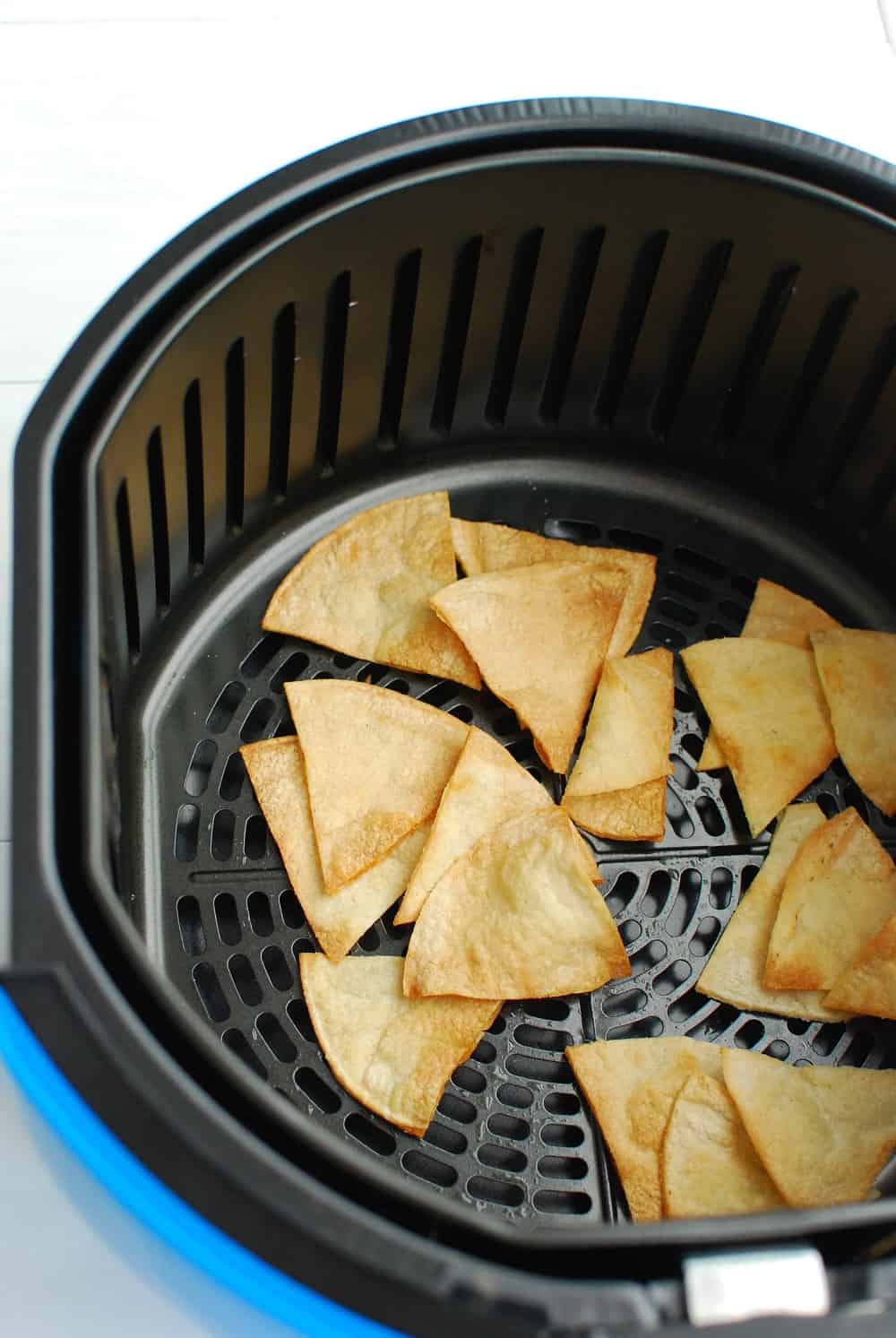 Air fryer tortilla chips in the air fryer basket.